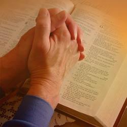 praying hands over Bible